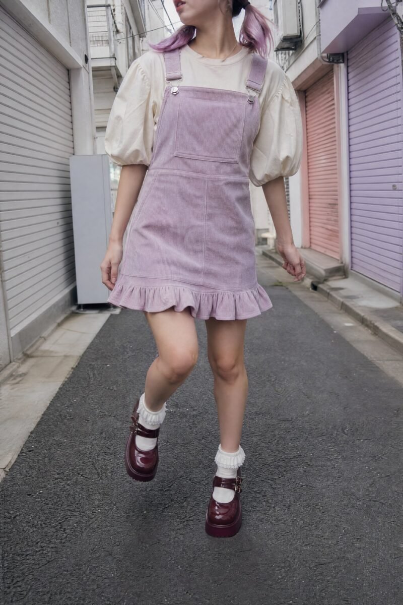 Corduroy Bib Pinafore — Fine-wale lilac corduroy with a square bib and adjustable strap buckles.