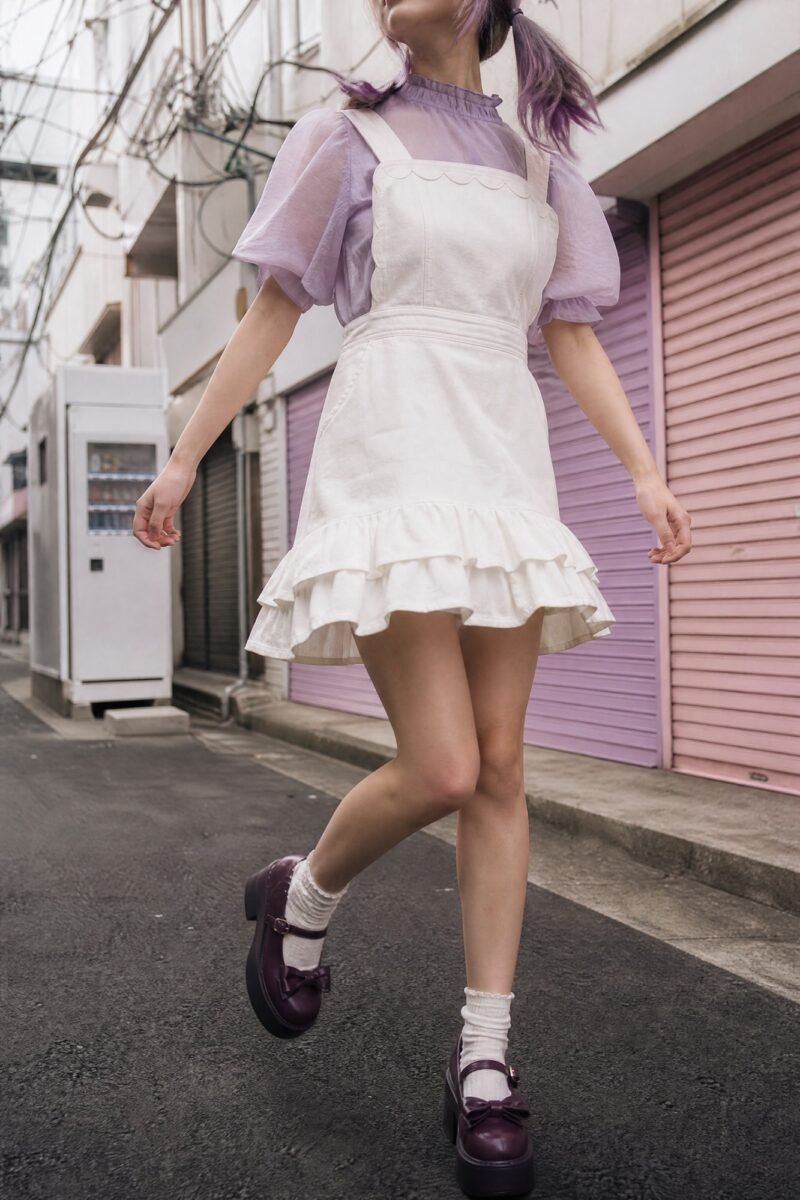 Ruffle-Hem Pinafore — Milk-white twill with a double ruffle at the hem and scalloped bib edges.